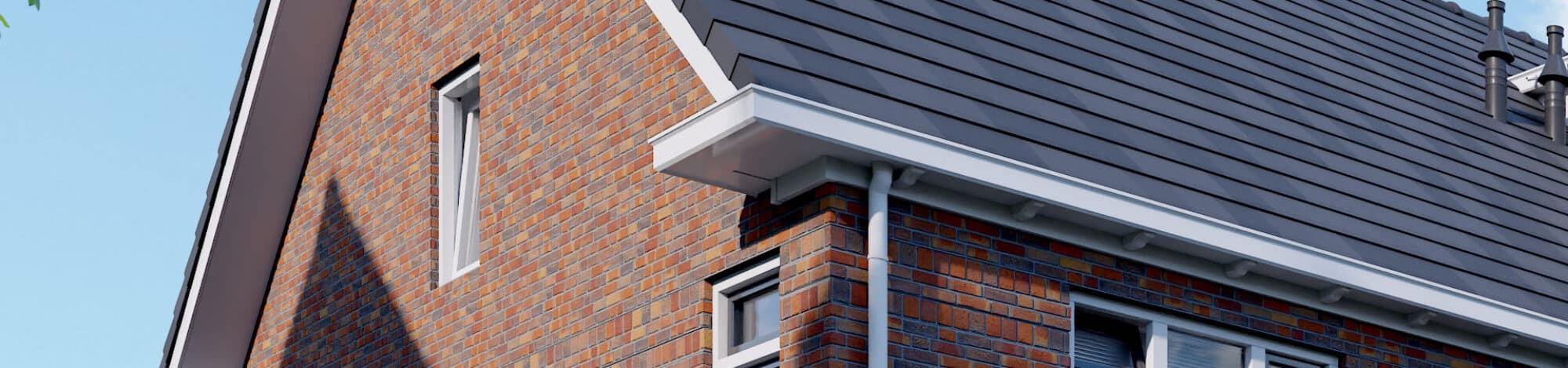 Een modern bakstenen huis met een steil grijs dak, rechthoekige ramen en witte randen, afstekend tegen een helderblauwe lucht.